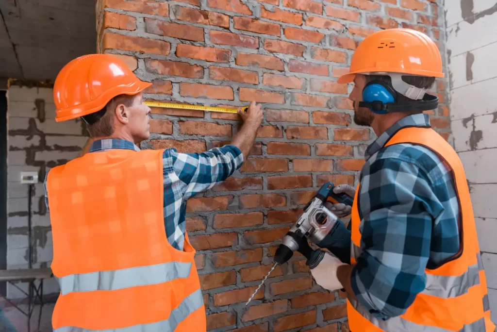 constructor measuring brick wall near coworker wit 2023 11 27 05 35 04 utc