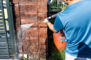 worker using high pressure water jet spray gun to clean brick