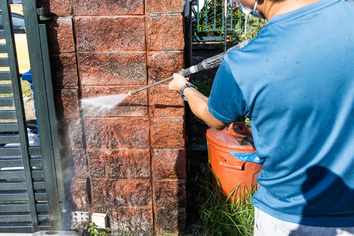 worker using high pressure water jet spray gun to clean brick